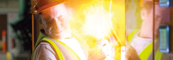 An electrician closing his eyes and turning away from a bright flash